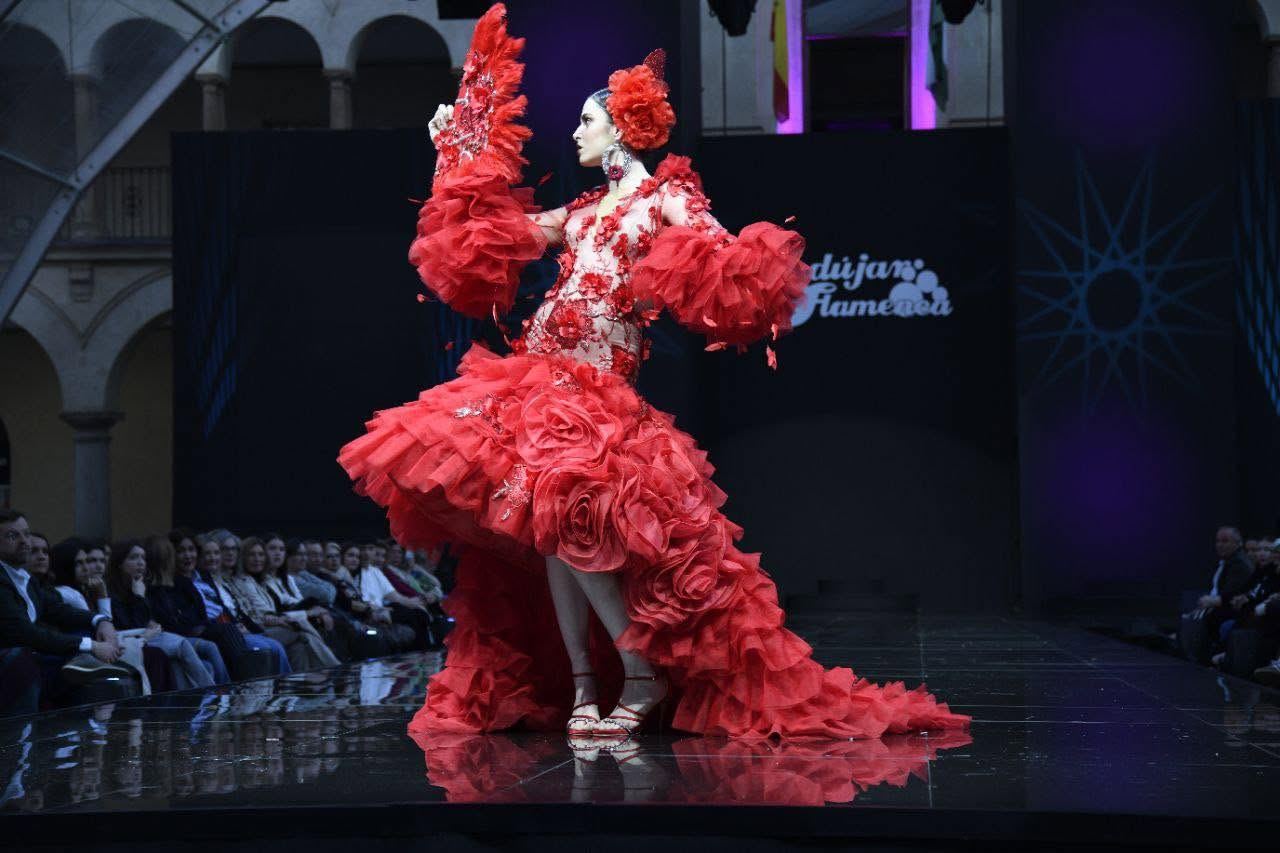Modelo con traje de flamenca rojo de volantes y flores de tul sobre la pasarela de Andújar Flamenca